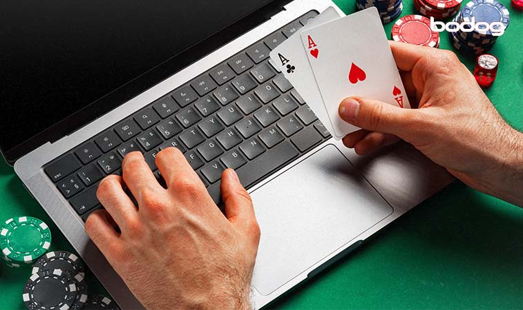 Manos masculinas sosteniendo dos cartas frente a una computadora