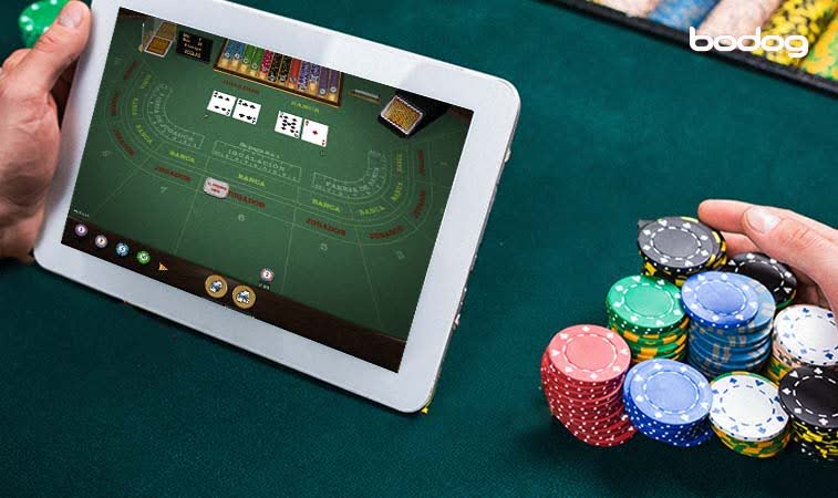Manos sosteniendo tablet y fichas de casino