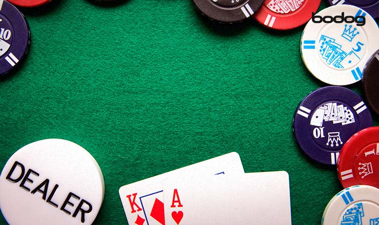 Cartas, fichas e um botão de dealer em uma mesa de poker
