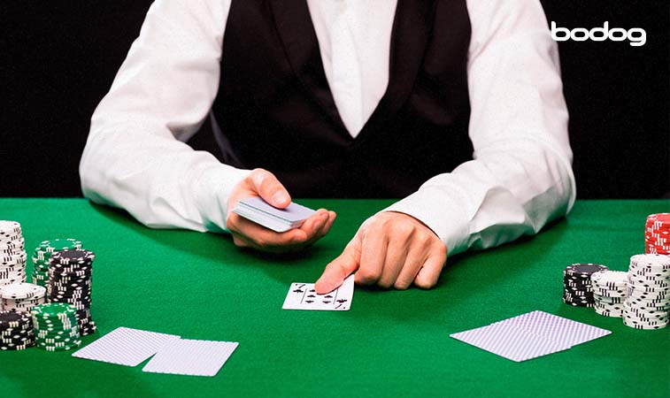Dealer colocando uma carta na mesa de poker. Fichas de poker estão ao lado