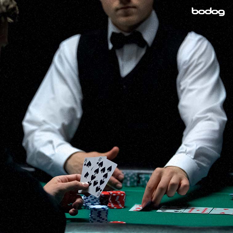 Pessoa com uma mão de duas cartas e Dealer colocando cartas comunitárias