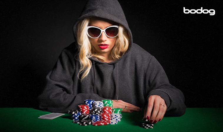 Jugadora de poker usando lentes de sol y moviendo fichas
