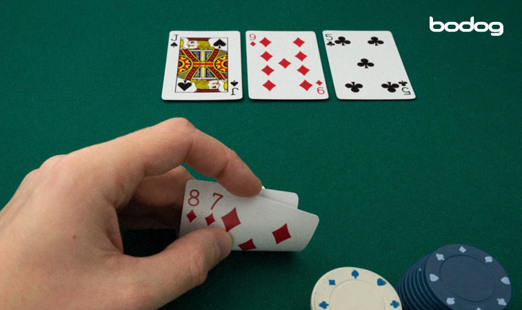 Pessoa segurando cartas 8 e 7, frente a um flop J, 9, 5