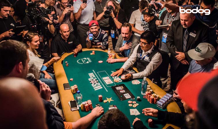 jogadores de poker em uma mesa da WSOP, cercadas por pessoas tirando fotos