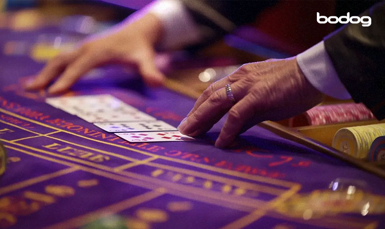 mesa de Baccarat com o banqueiro mexendo nas cartas