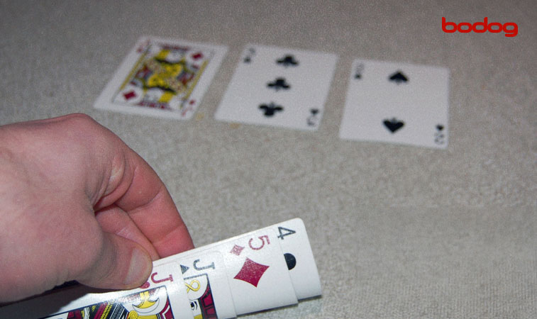 Mão levantando as cartas de poker discretamente: 4, 5, J, J