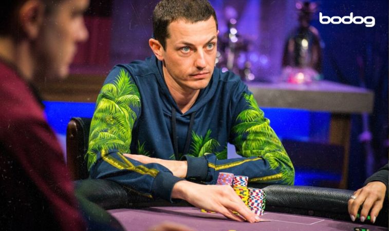 Tom Dwan com suas cartas e fichas em torneio de poker