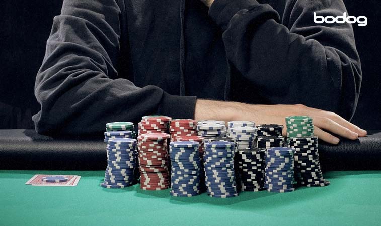 Pessoa com um monte de fichas de poker sobre a mesa